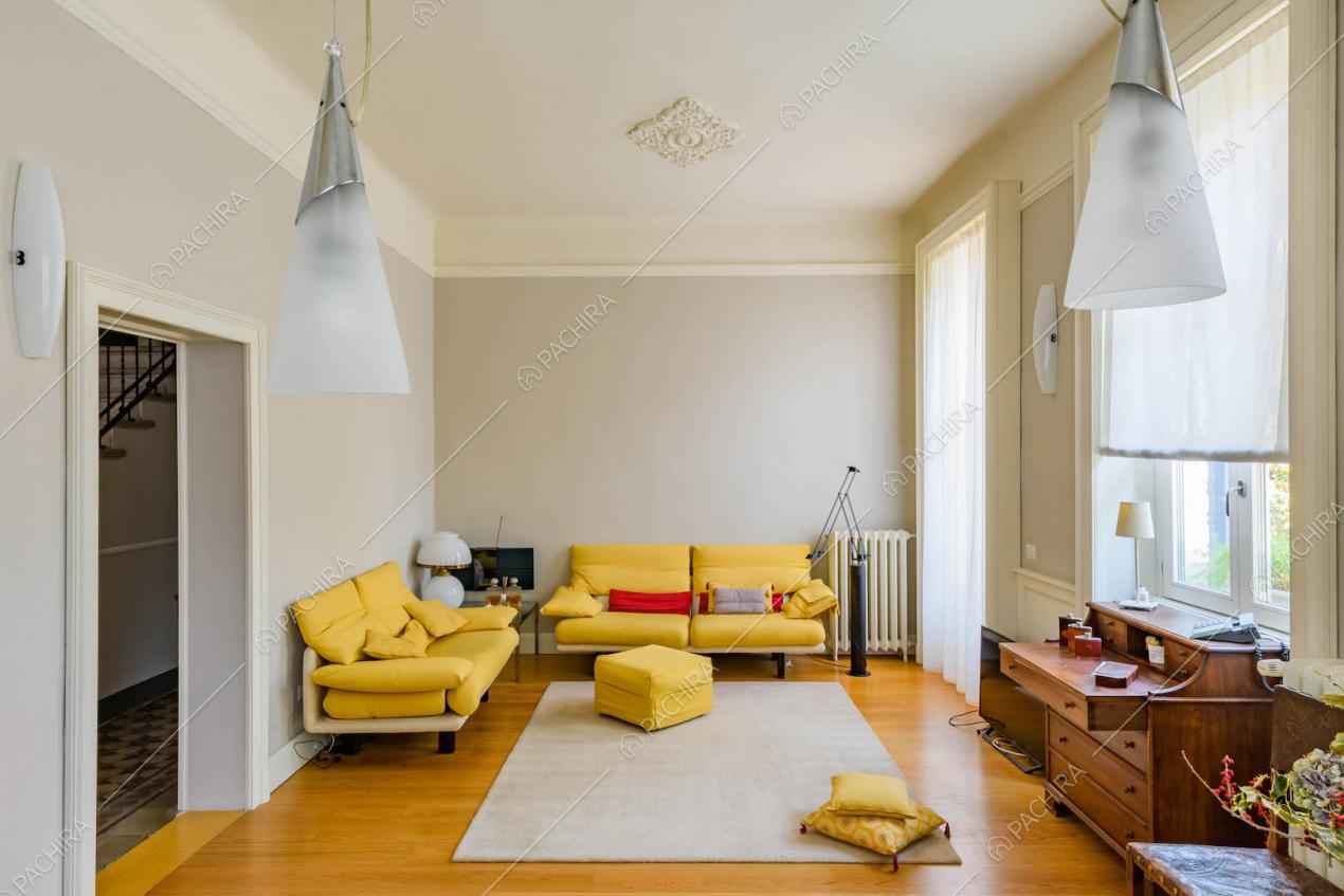 Luminoso salotto con divani gialli, pavimento in parquet e pareti grigie con boiserie