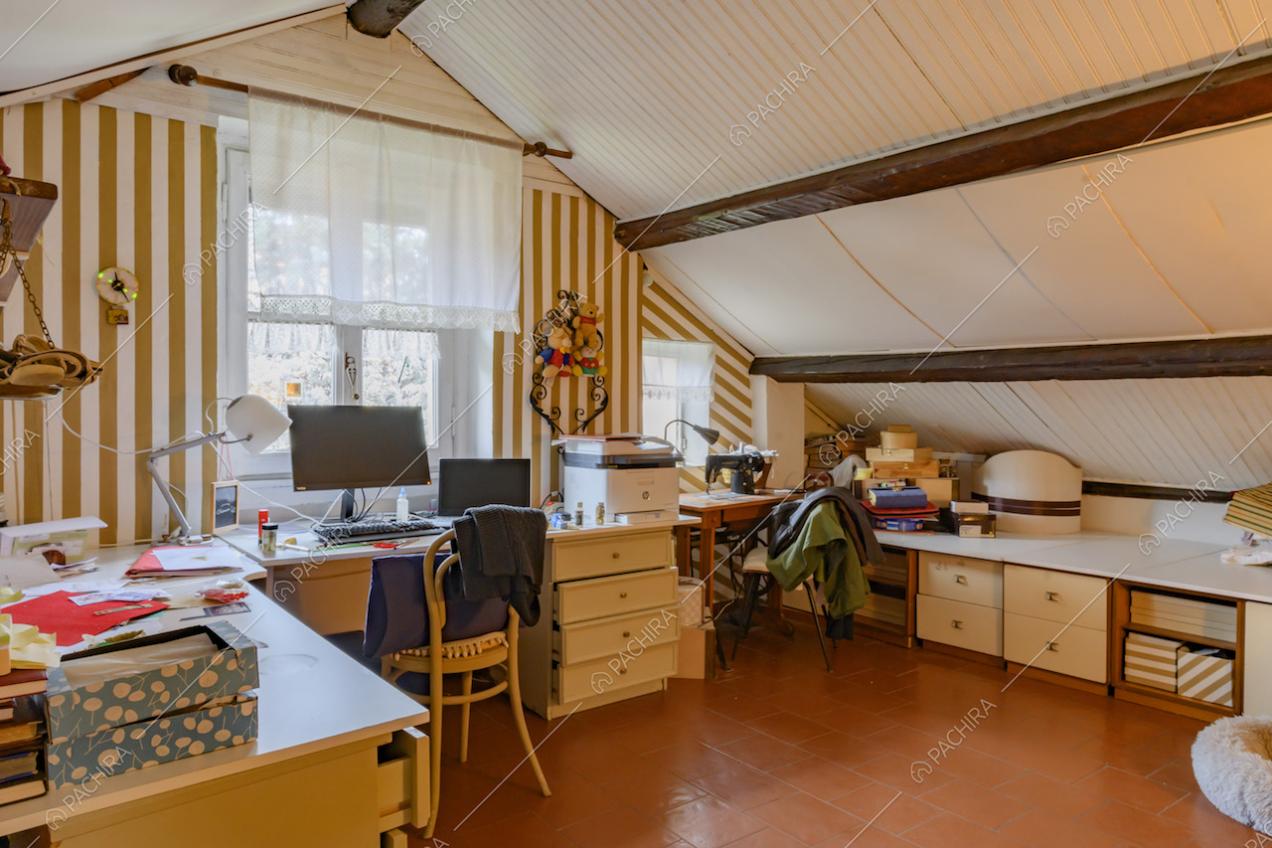 Nel solaio soffitto bianco con travi a vista, scrivania e pavimento in cotto