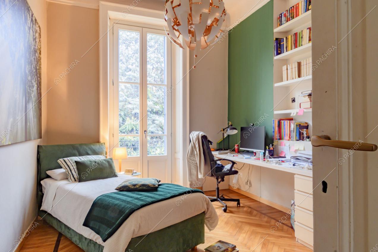 Camera da letto con pavimento in parquet a spina di pesce, parete verde e scrivania