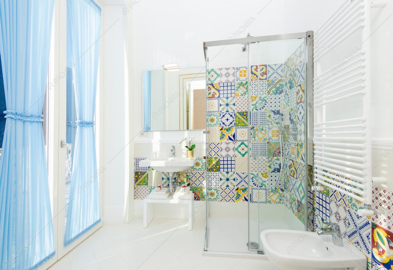 Bagno con doccia, specchio, sanitari e tende azzurre