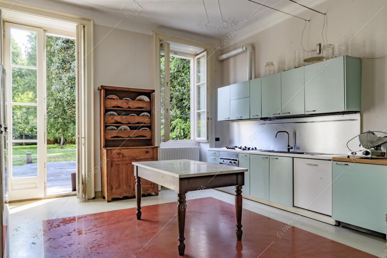 Cucina a muro azzurra con fornelli a gas e pavimento rosso e bianco, illuminata di luce naturale