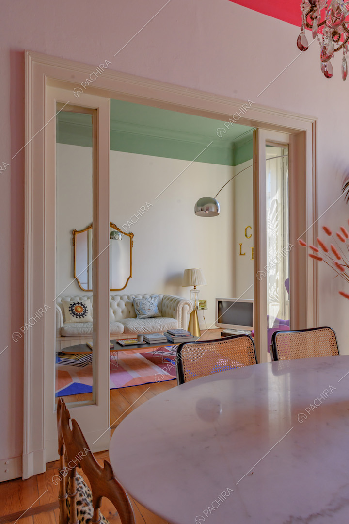 Dal tavolo bianco della sala da pranzo vista sul salotto attraverso la porta a vetri