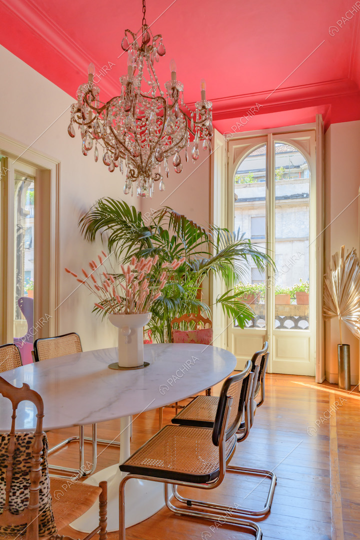 Sala da pranzo con porta-finestra bianca, pavimento in parquet e soffitto fucsia con boiserie