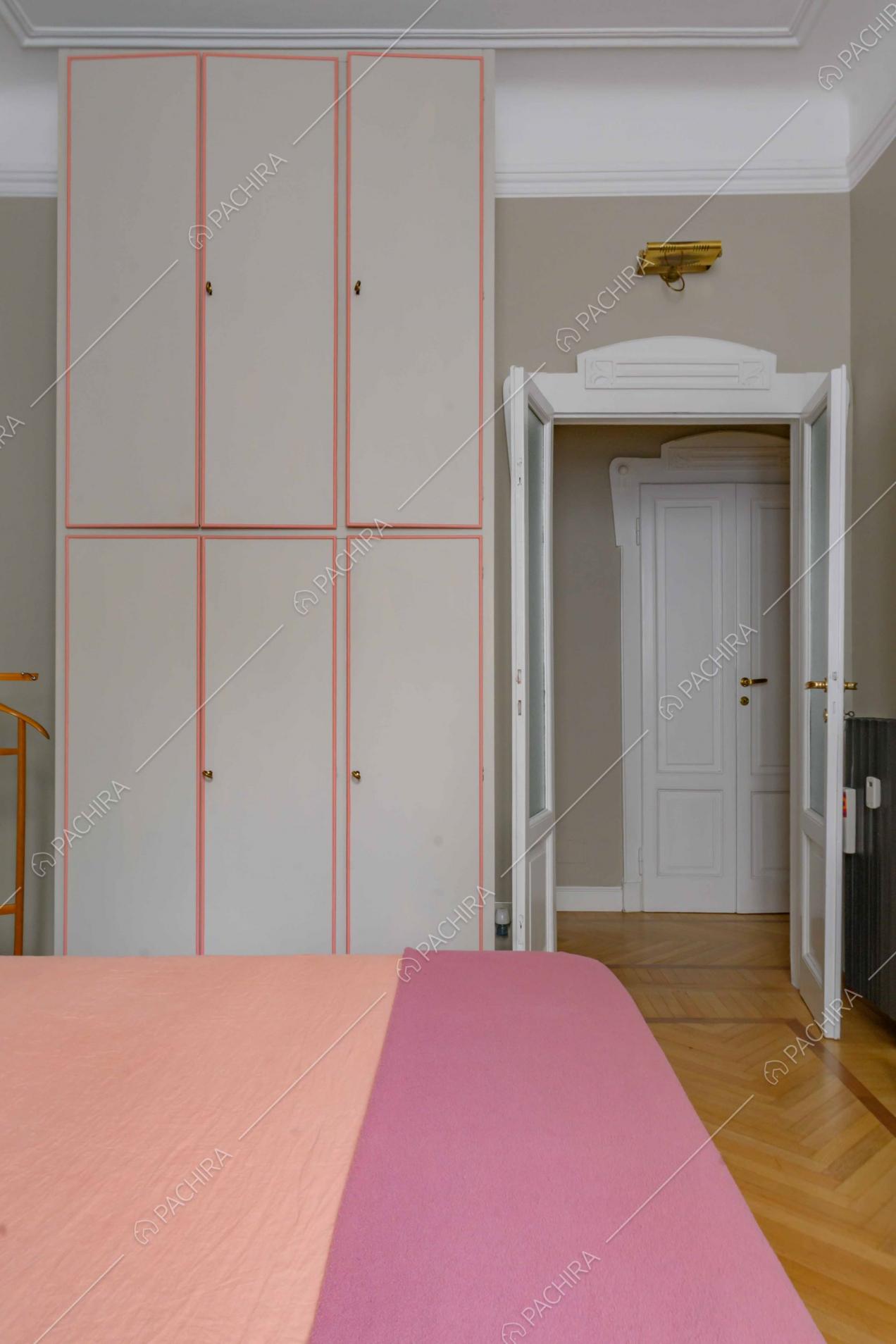 Armadi a muro e alti soffitti nella camera da letto in parquet a spina di pesce