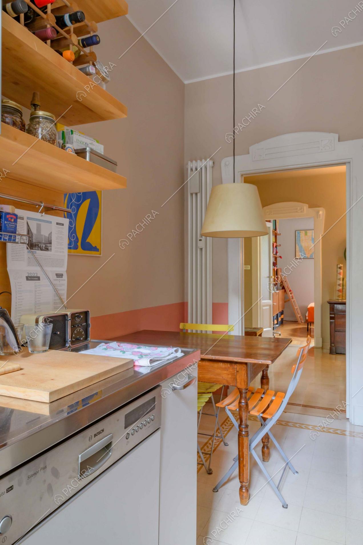 Cucina della location dalle pareti rosa e con tavolo da pranzo in legno