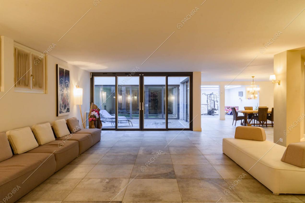 Luminoso salotto con pouf, porte-finestre nere e vista sul tavolo da pranzo