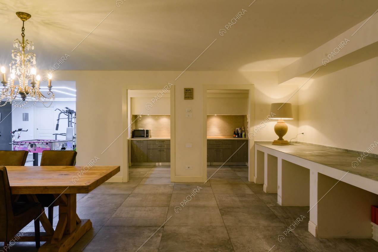 Grande sala con vista sulla cucina a parete, tavolo da pranzo in legno e palestra