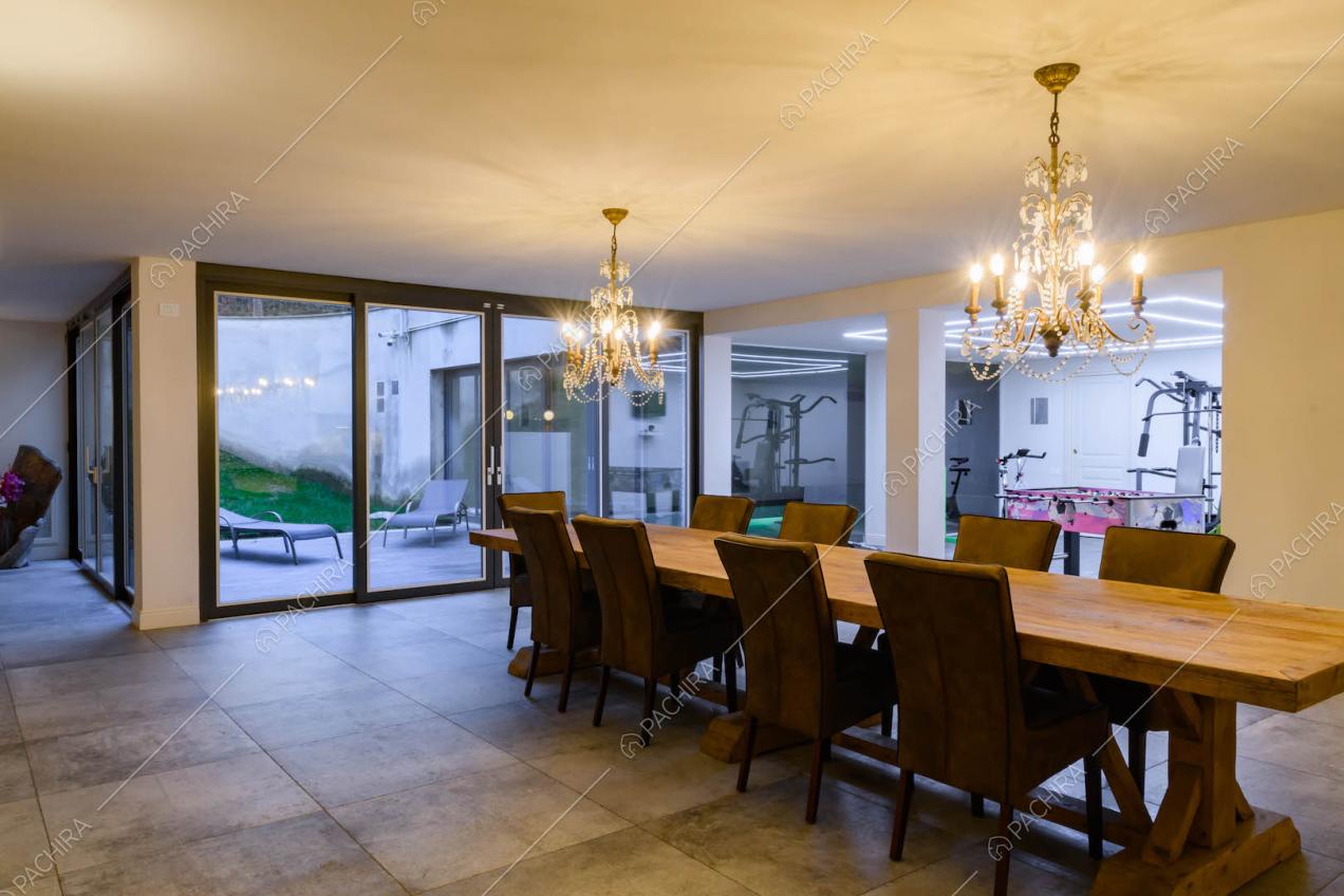 Tavolo da pranzo in legno nella sala al pianterreno con ampie vetrate e palestra