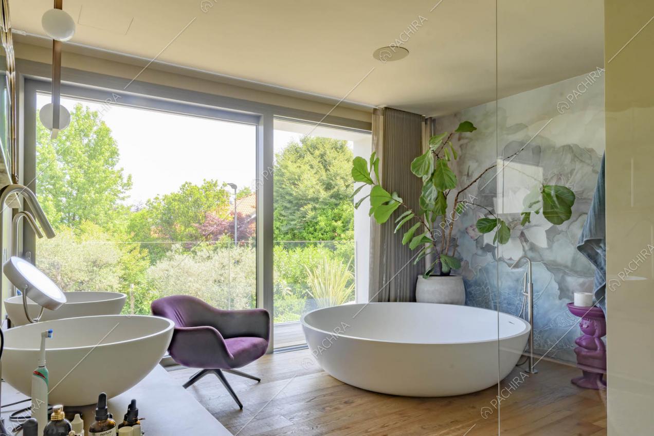 Bagno con vasca, pavimento in parquet, carta da parati e porta-scorrevole con vista sul parco