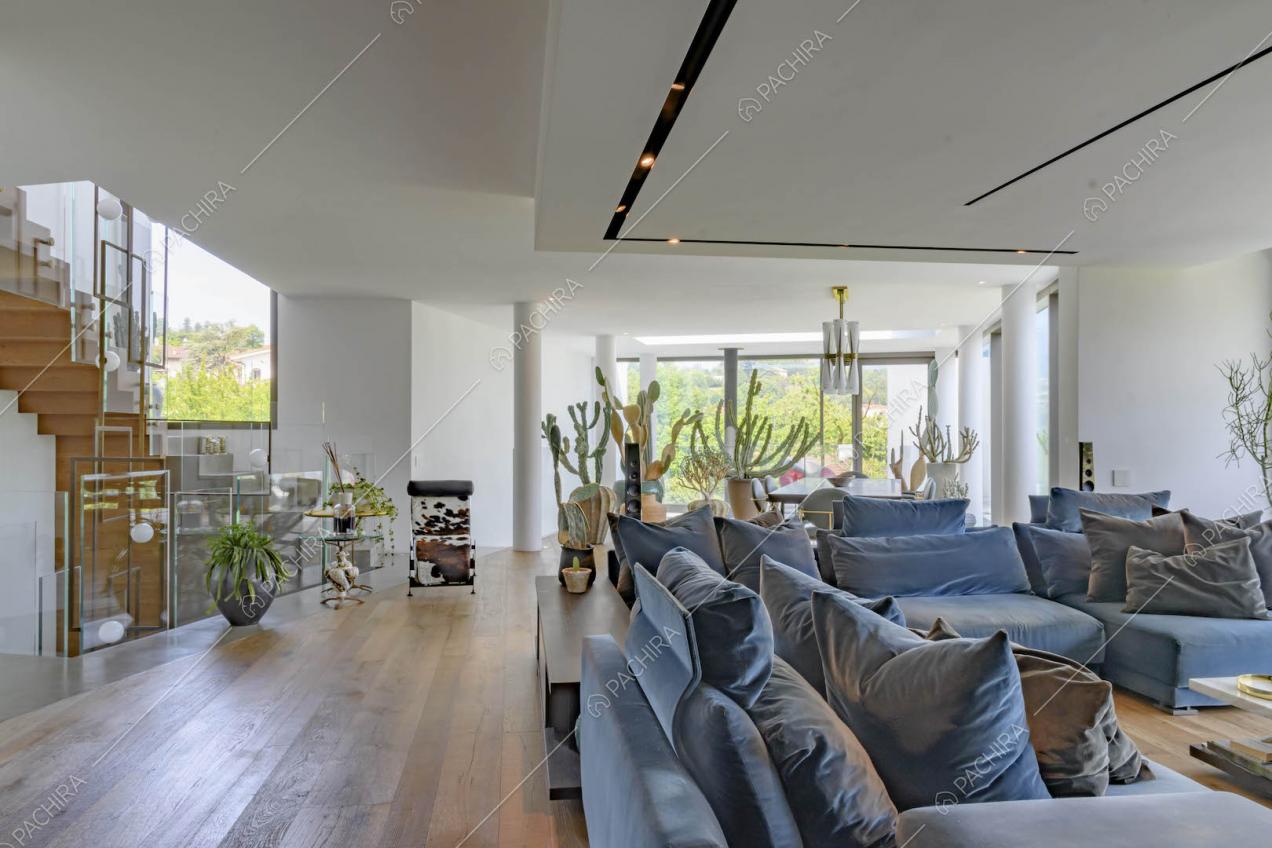 Sala con pavimento in parquet, divani blu, pareti bianche e scale