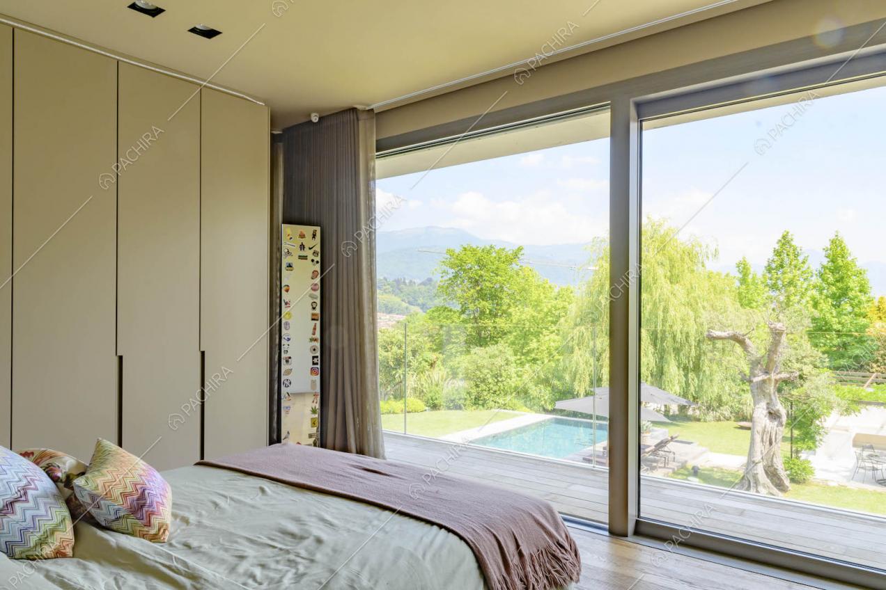 Camera da letto con pavimento in parquet, armadi a muro e porta-finestra scorrevole che conduce al balcone