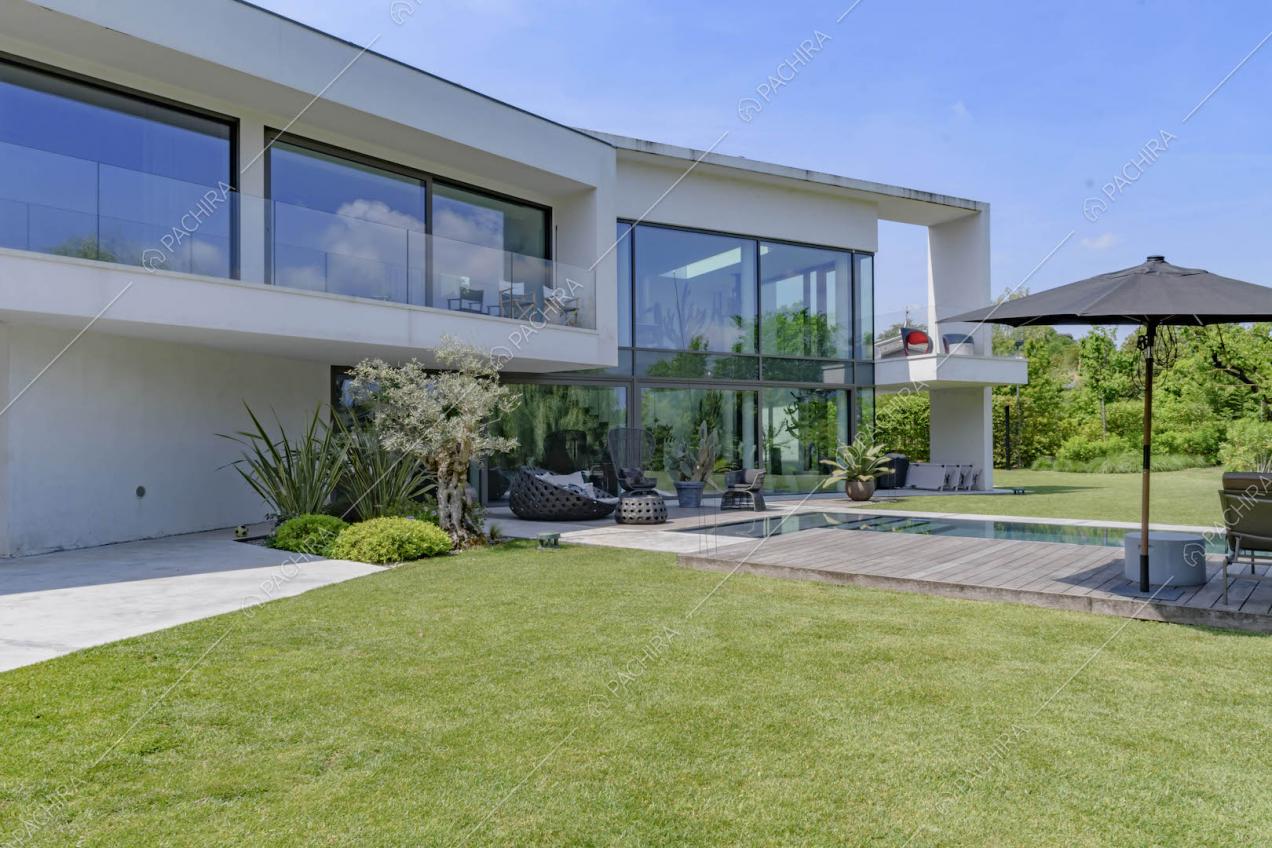 Dal curatissimo giardino con piscina vista sul portico e sul balcone con ringhiera in vetro