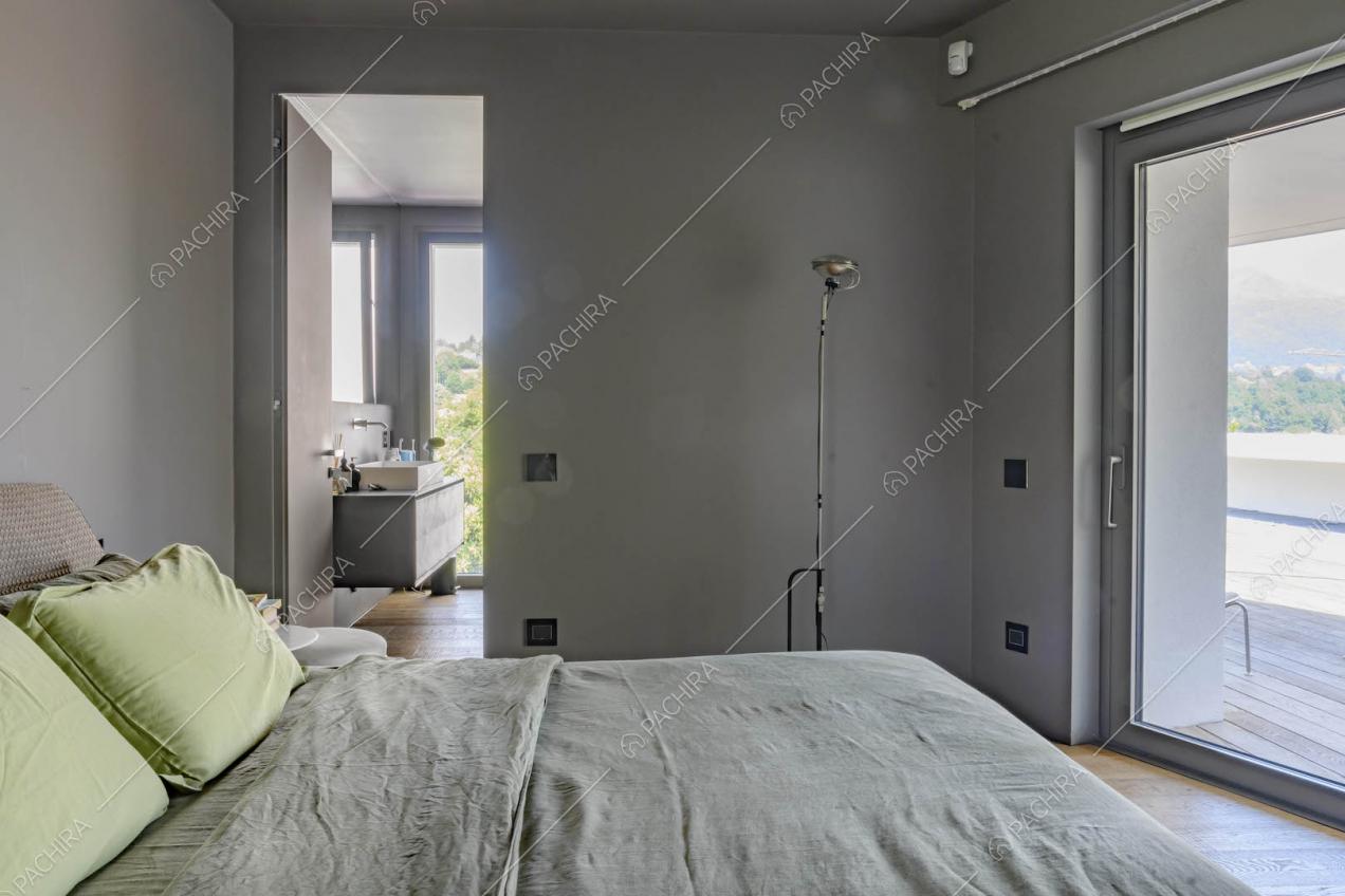 Camera da letto matrimoniale con pavimento in parquet, pareti grigie e bagno privato