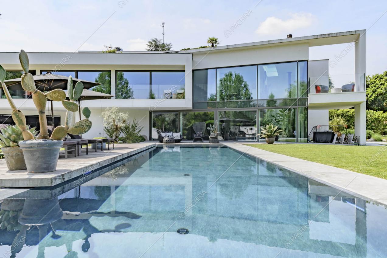 Dalla grande piscina nel giardino vista sulla location con grandi vetrate e veranda