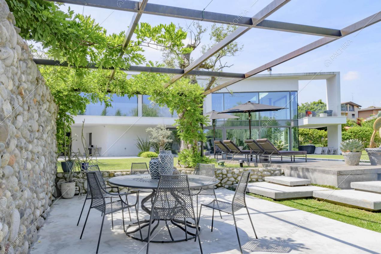 Veranda con parete in pietre a vista e tavolo da pranzo e sedie in metallo nero 