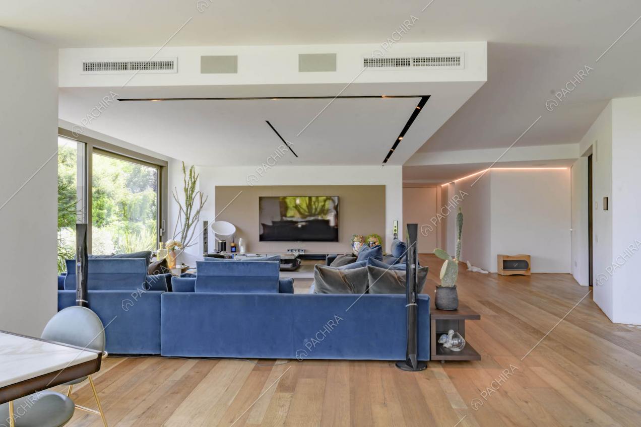 Pavimento in parquet nella luminosa sala con divani blu e grandi vetrate