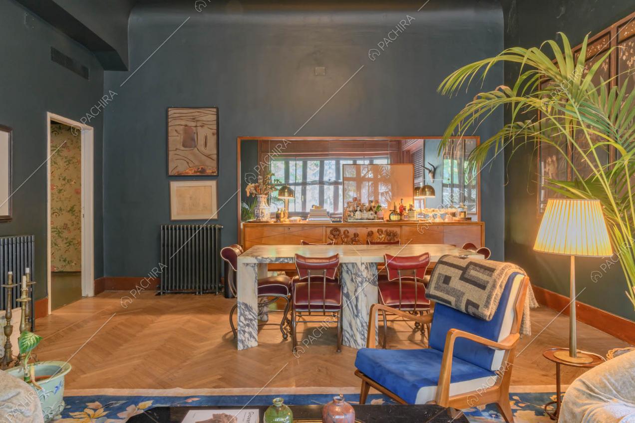 Salotto con pavimento in parquet a spina di pesce, tavolo da pranzo e pareti blu