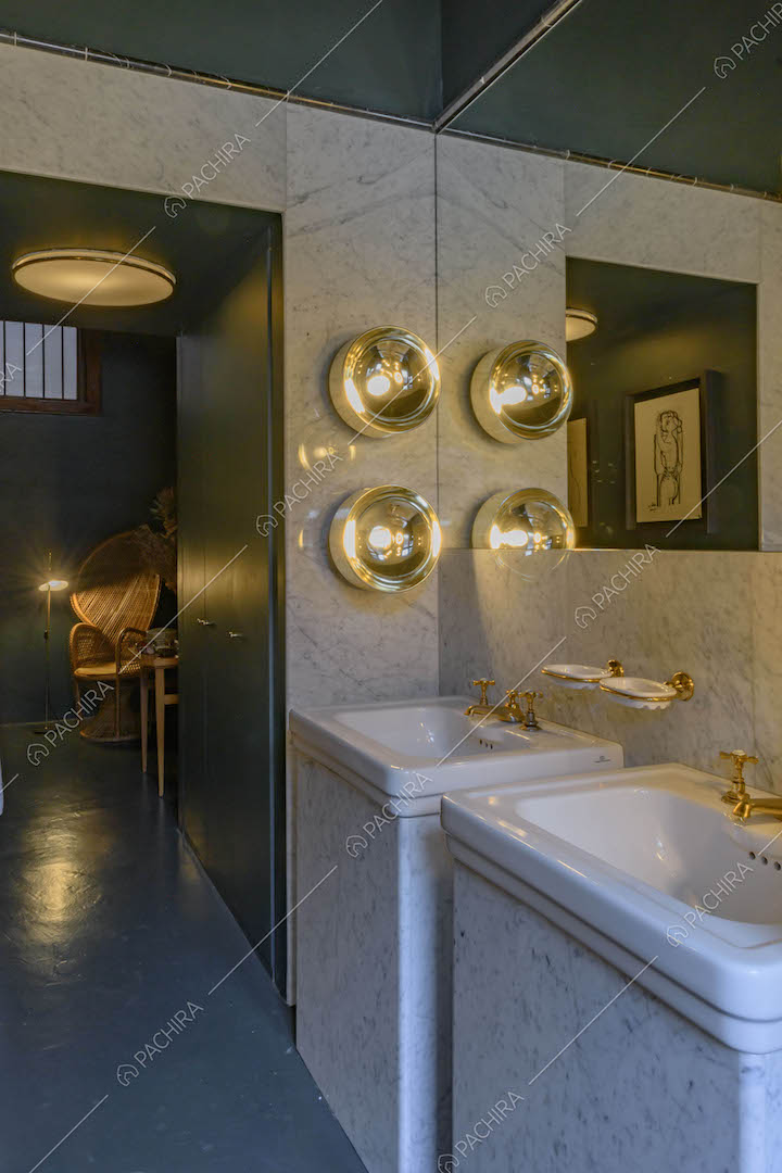 Lavandini nel bagno con grande specchio, parete in marmo e pavimento blu