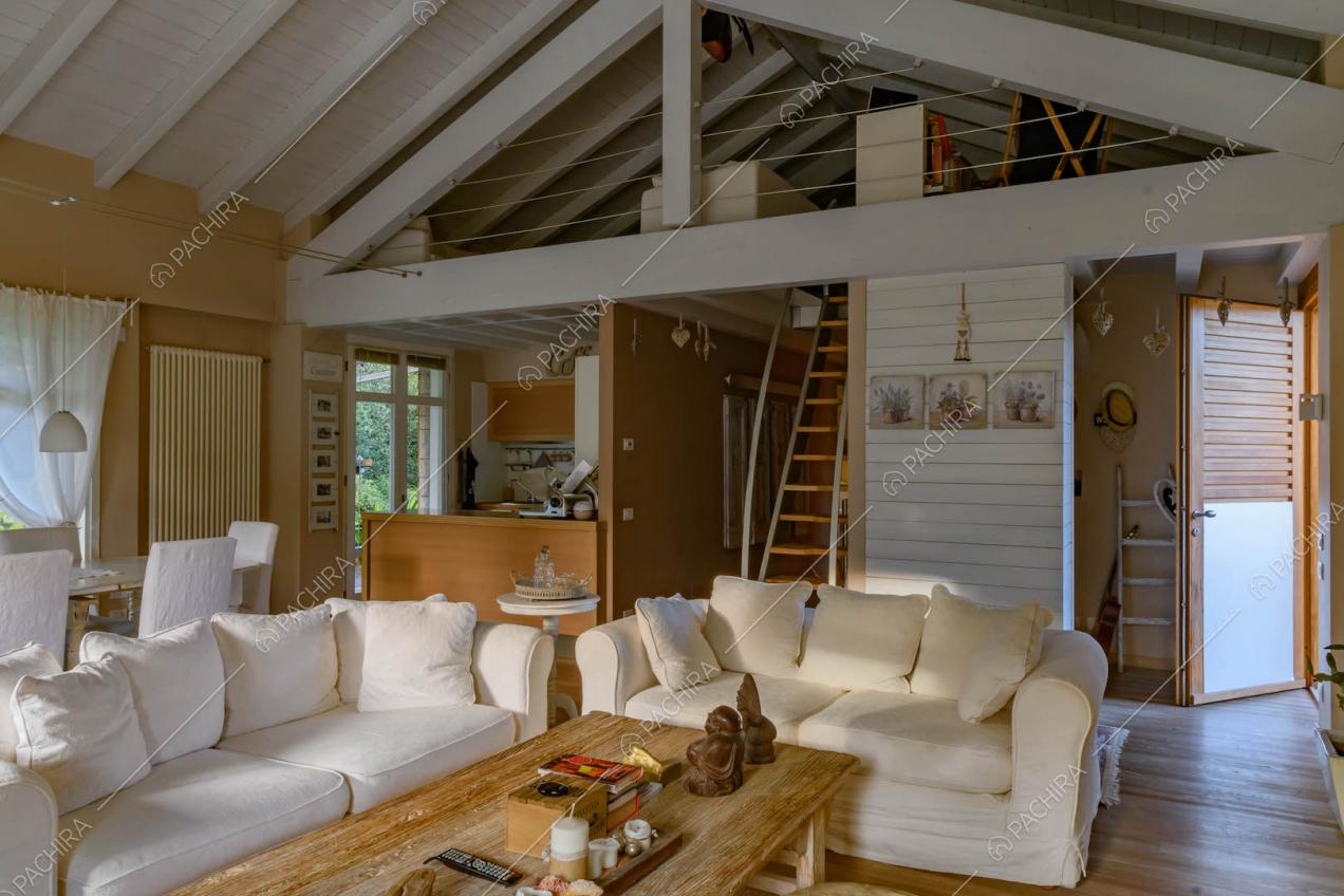 Salotto con divani bianchi, pavimento in parquet e vista sul soppalco