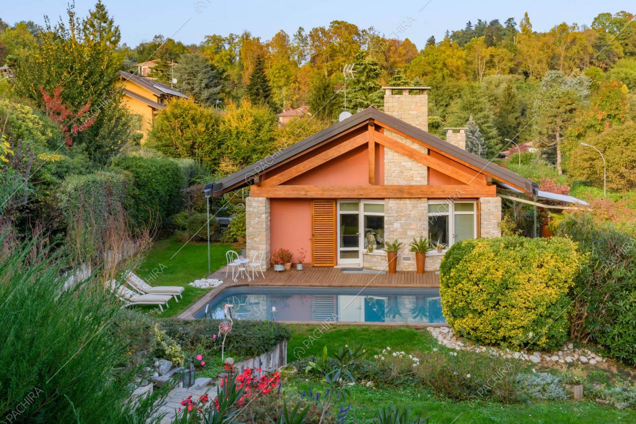 Vista sul curato giardino con piscina, pavimentazione in parquet ed esterni rossi