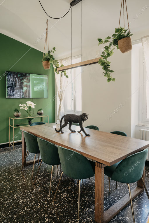 Tavolo da pranzo nella sala con pavimento in graniglia nero e parete verde