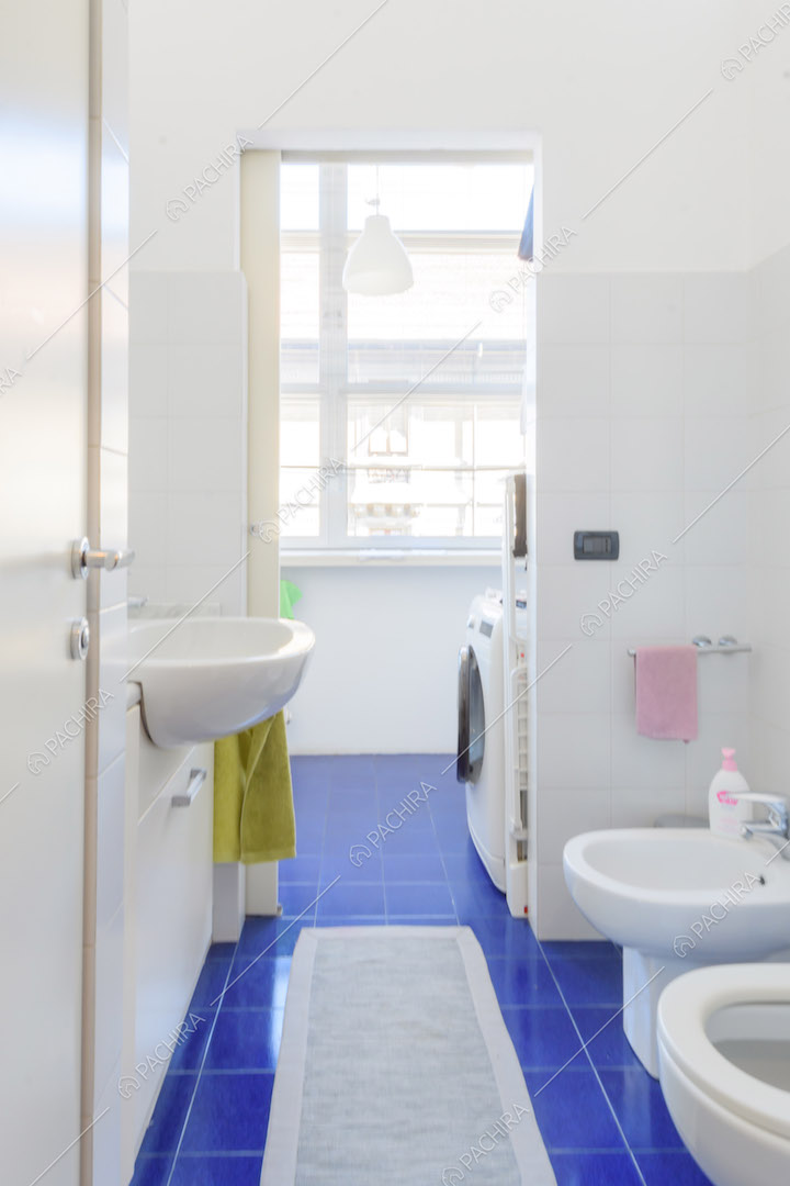 Luminoso bagno con pavimento in piastrelle blu e pareti bianche