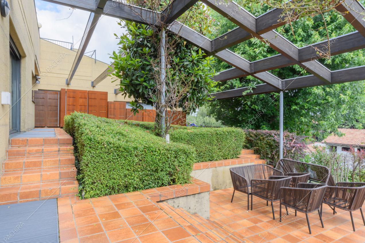 Terrazza con piastrelle marroni, poltrone da esterno e struttura nera