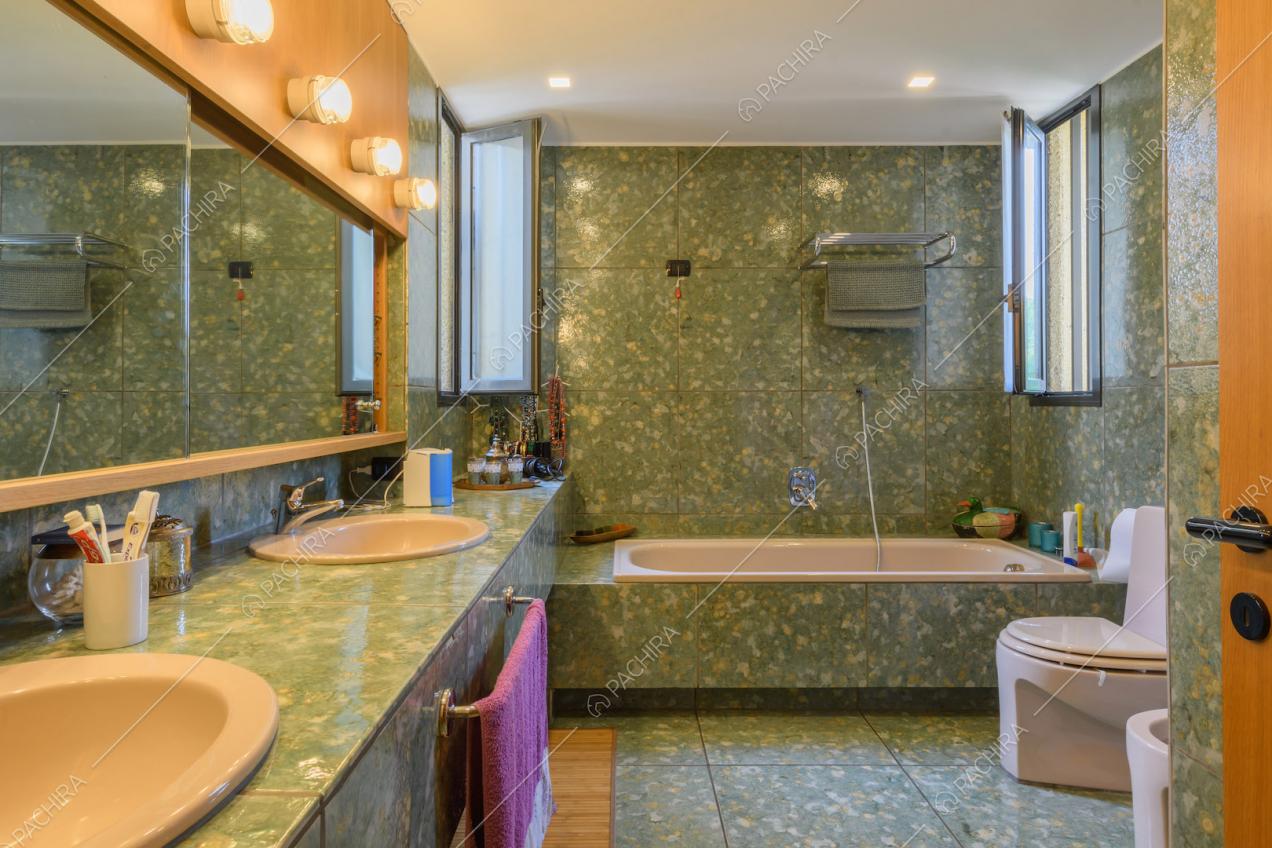 Grande bagno con pareti e pavimento in marmo verde e vasca