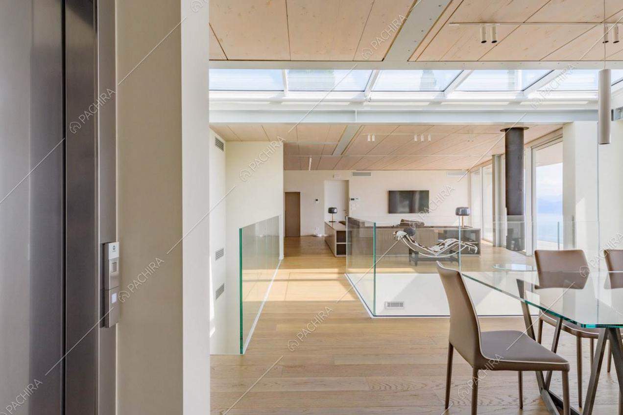 Ascensore nella grande sala con tavolo da pranzo, lucernari e pavimento in parquet