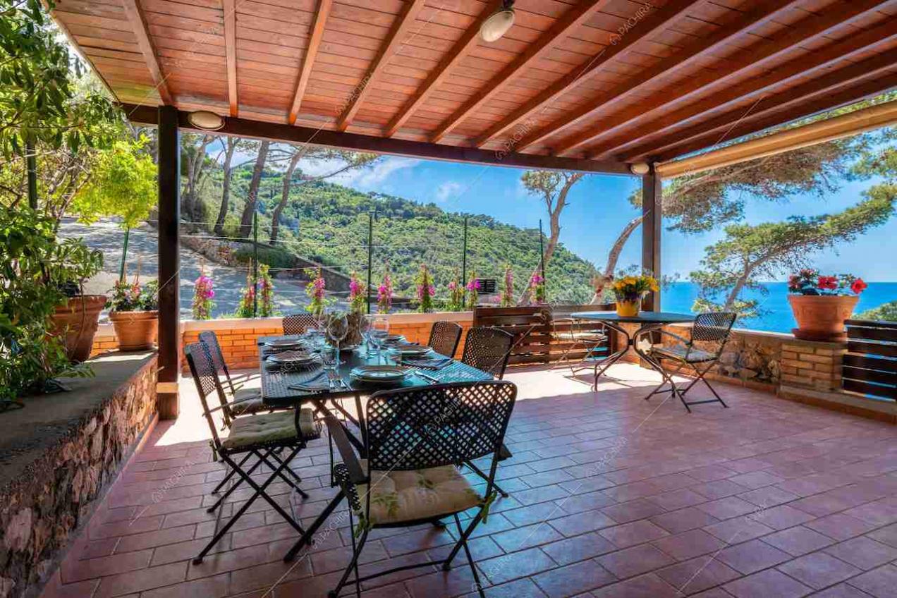Veranda con soffitto in travi in legno, tavolo da pranzo e vista sul mare