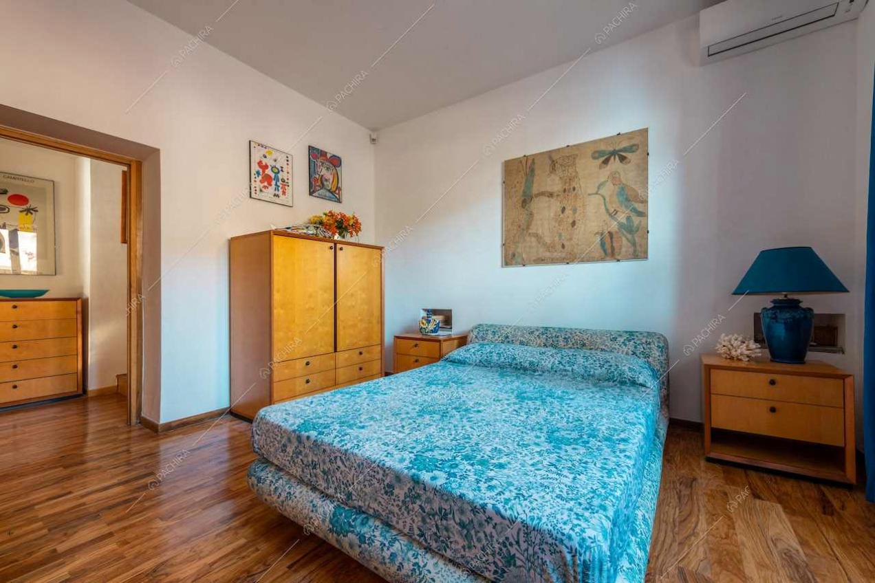 Camera da letto matrimoniale con pareti bianche e pavimento in parquet