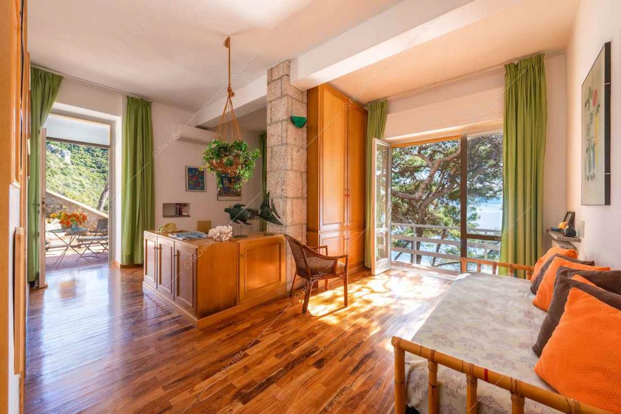 Pavimento in parquet, tende verdi e grande vetrata con vista sul mare