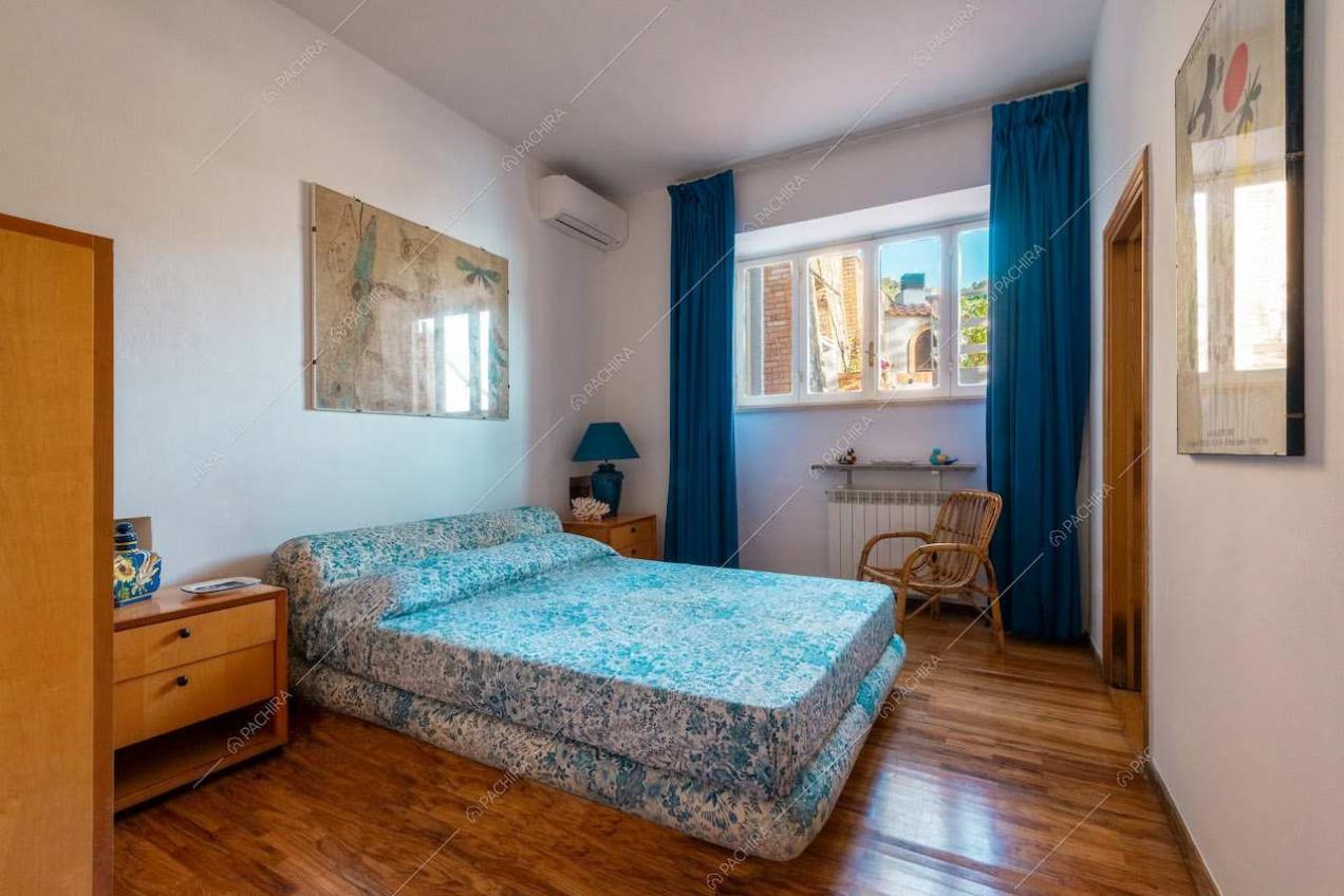 Letto matrimoniale nella camera con pavimento in parquet e tende blu