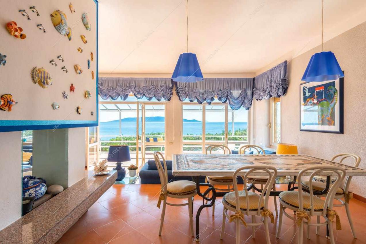 Tavolo da pranzo nella luminosa sala con porte-finestre e vista sul mare