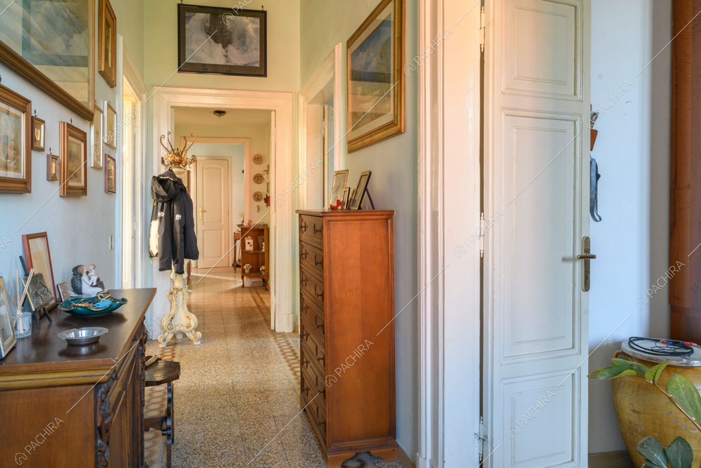 Corridoio con pavimento in graniglia e vista sulla porta bianca con boiserie