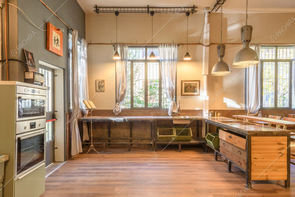 Pavimento in parquet nella luminosa cucina con fornelli a induzione e vetrate industriali