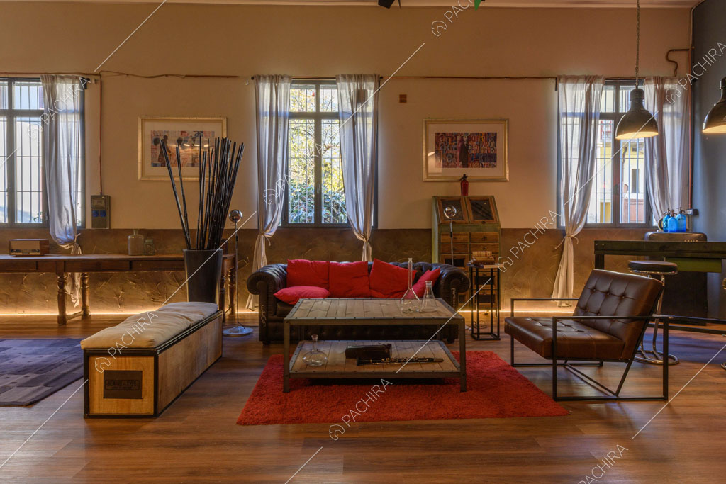Poltrona marrone in pelle, pouf e divano nero nell'open space con pavimento in parquet