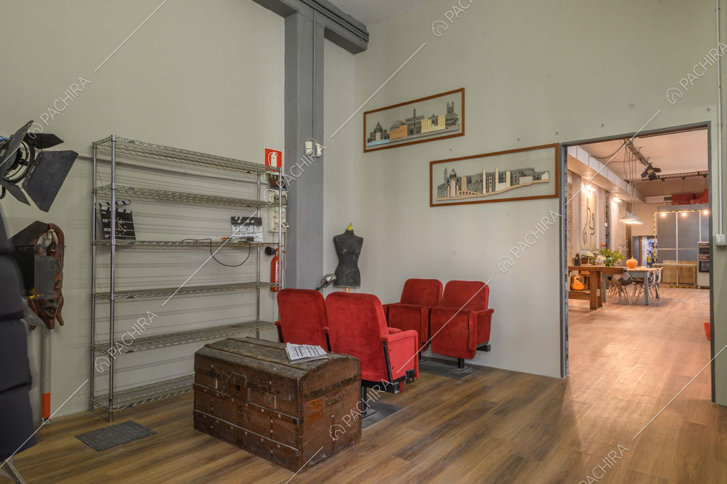 Poltrone rosse da cinema nell'atrio con pavimento in parquet e vista sull'open space