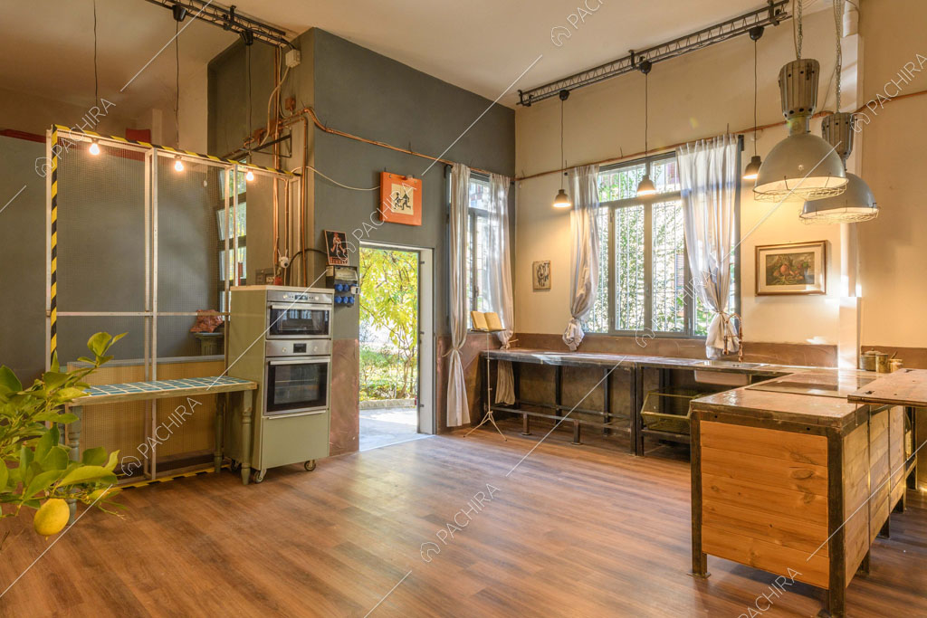 Luminosa cucina con fornelli a induzione, pavimento in parquet e parete blu petrolio