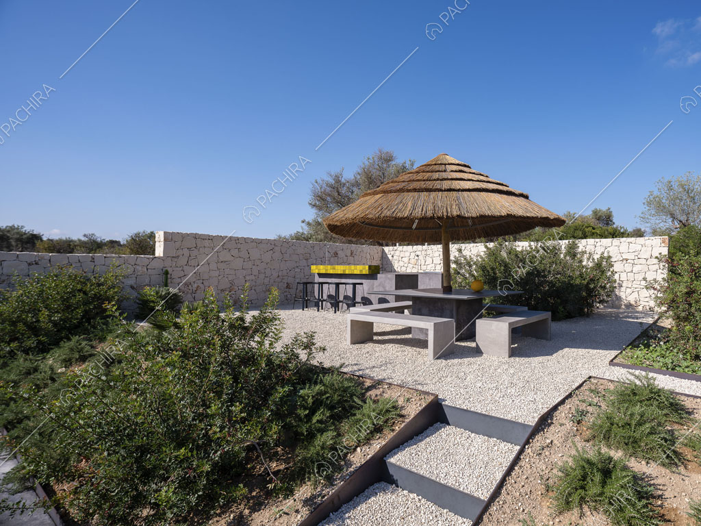 Giardino con ombrellone in paglia, panchine e mura bianche