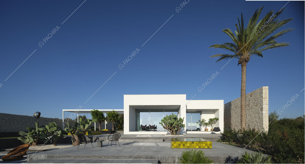 Vista sugli esterni bianchi della piscina con grandi vetrate e patio