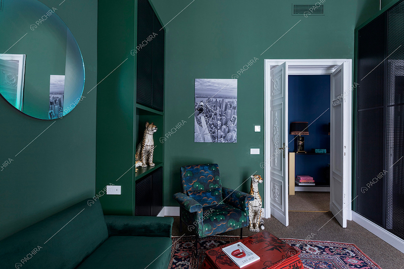 Pareti verdi dello studio con divanetto in velluto e moquette sul pavimento