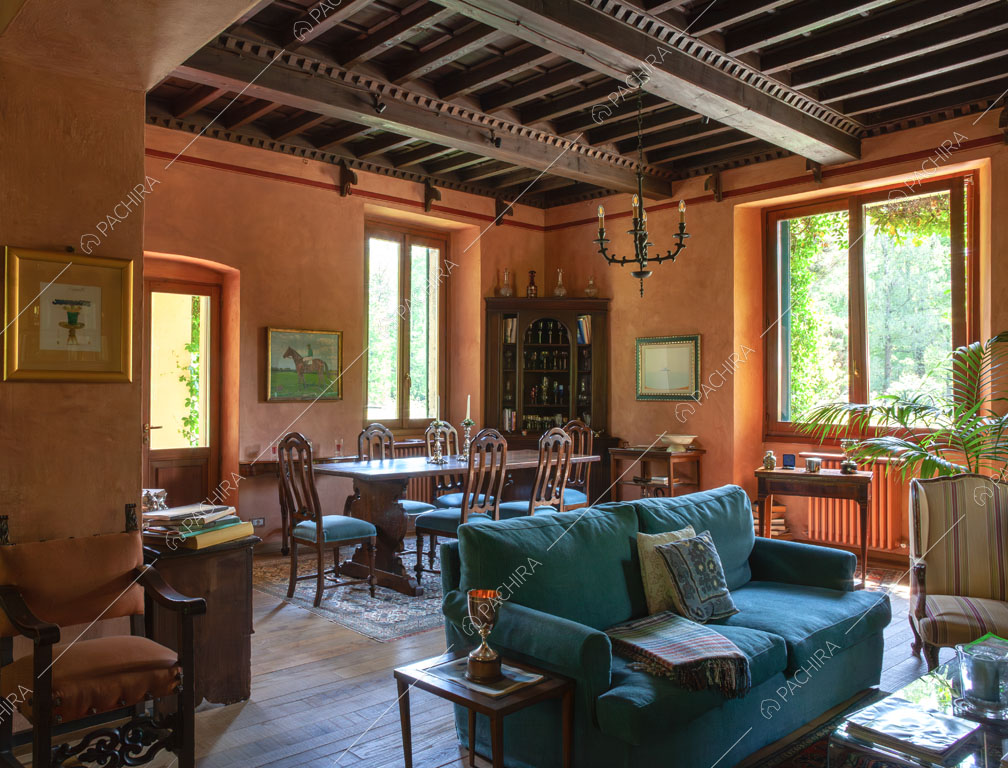 Divano blu nella sala con tavolo da pranzo in legno e soffitto a cassettoni