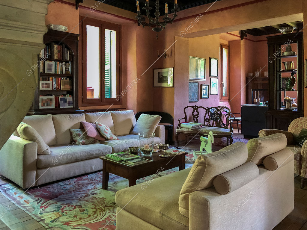 Divani nella luminosa sala con pavimento in parquet e lampadario antico