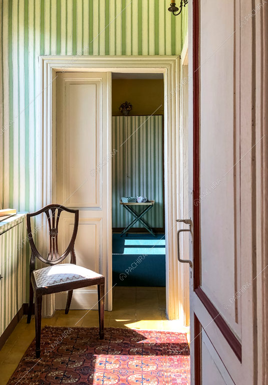 Luminoso corridoio con carta da parati a righe e boiserie sulle porte