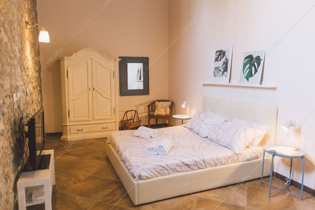 Parete in pietra a vista della camera da letto della villa Hibiki, location in stile moderno a Siracusa
