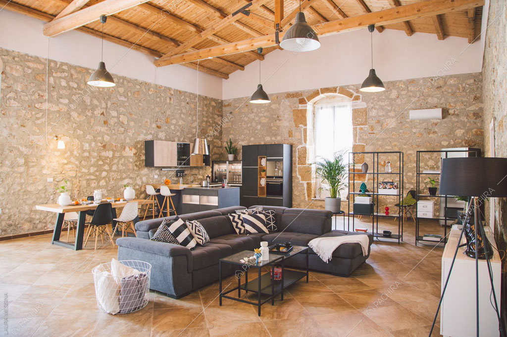 Zona living con pareti in pietra a vista della villa Hibiki, location in stile moderno a Siracusa