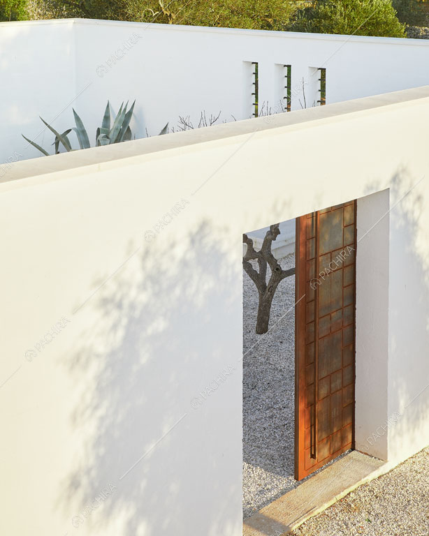 Mura bianche e porta scorrevole nel giardino della masseria Ryn, location in stile contemporaneo a Brindisi