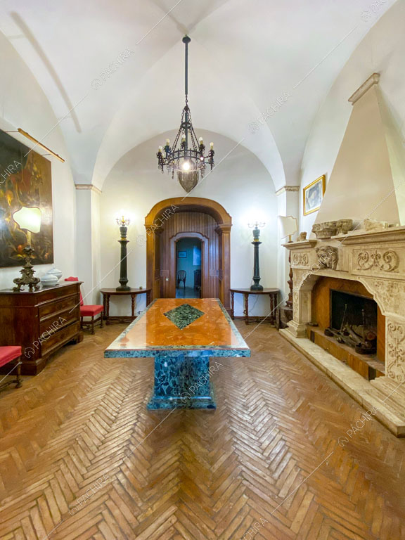 Sala con pavimento in parquet a spina di pesce, lampadario antico e grande camino in marmo