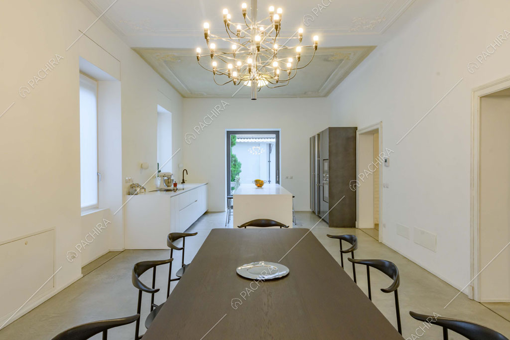Dal tavolo da pranzo nero vista sulla cucina con isola e sul lampadario antico